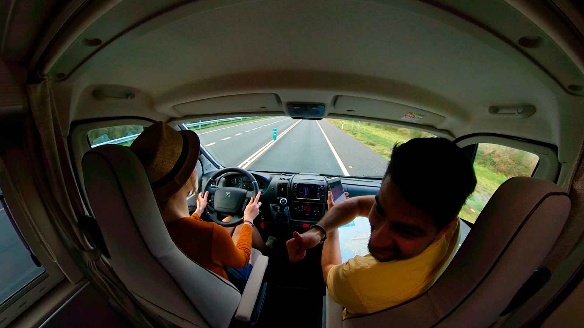 visión ultrangular del interior de una furgoneta camper con 2 jóvenes
